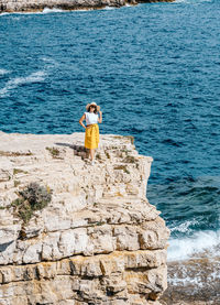 Young woman in summer clothes and hat on cliffs above sea. waves, nature, summer, travel.