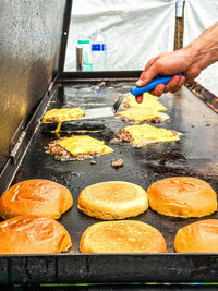 Cropped hand of man cooking burgers on the grill