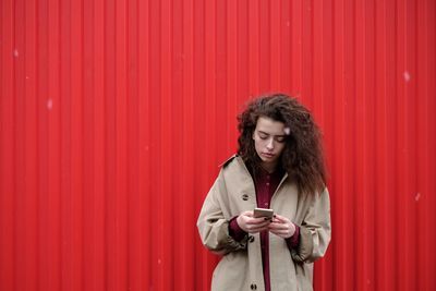 Young woman standing against yellow wall