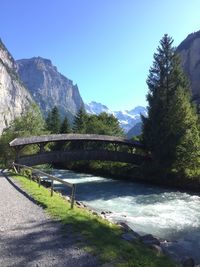 Scenic view of river by mountains against clear blue sky