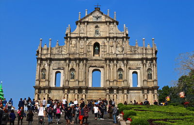 Tourists visiting ruins of st paul against clear blue sky