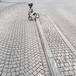 Boy riding tricycle on footpath