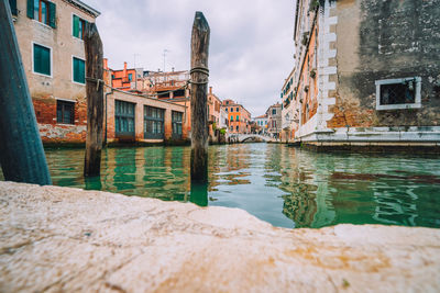 Canal by old buildings against sky in city