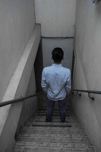 Rear view of man walking on staircase