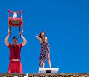 Young couple standing against blue sky