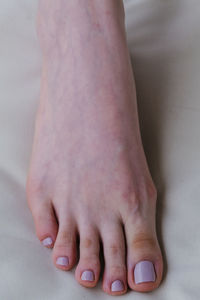 Close-up of female feet painted grey nail polish, self made pedicure at home.