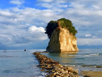 Rock formation on beach against sky