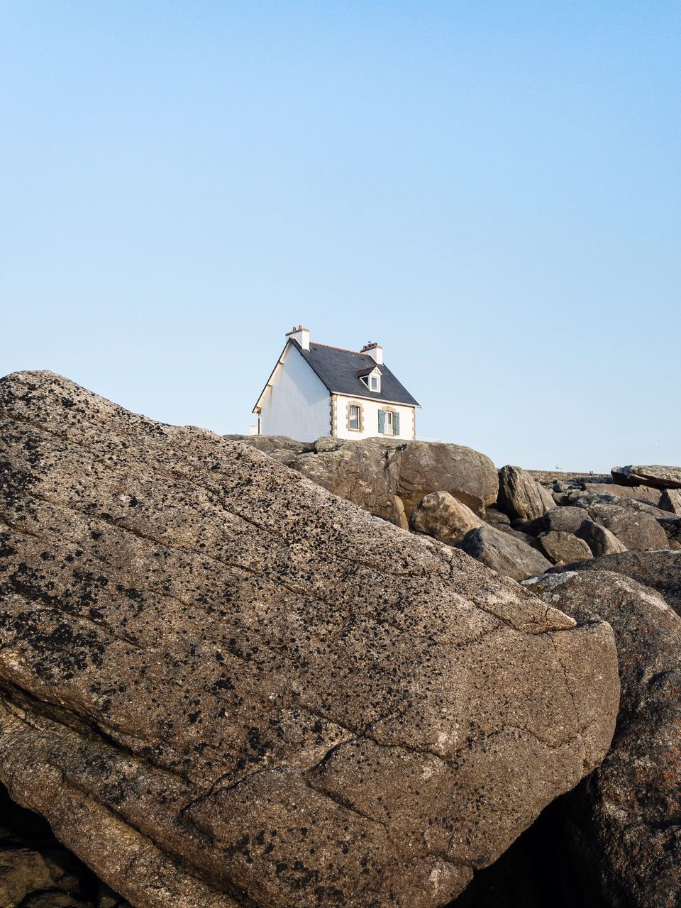 sky, built structure, architecture, clear sky, copy space, building exterior, building, rock, solid, low angle view, nature, no people, day, rock - object, house, blue, outdoors, sunlight, roof, land, stone wall