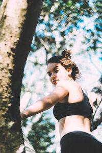 Low angle view of woman looking at tree trunk