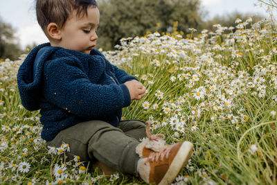 Side view of a boy sitting on field