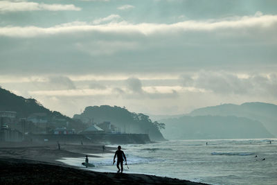 Man standing on beach against sky in foggy morning