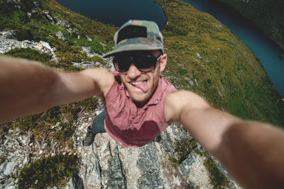 High angle portrait of man wearing sunglasses while standing on mountain