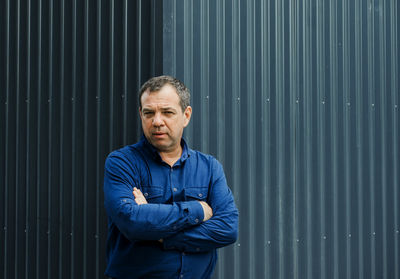 Portrait of man standing against corrugated iron