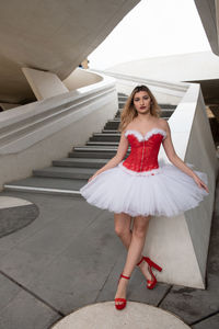 Portrait of young woman standing on footpath