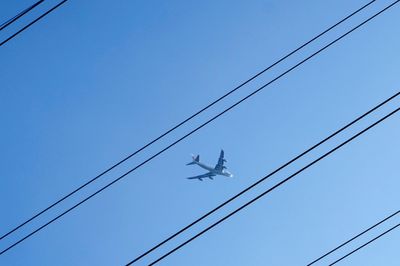 Low angle view of electricity pylon against blue sky
