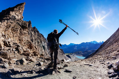 Full length rear view of mature man holding hiking poles standing at mountain