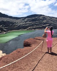 Rear view of woman standing on mountain against sky