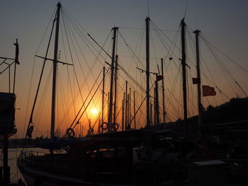 Sailboats moored at harbor during sunset