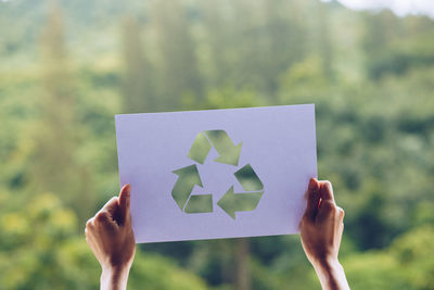 Close-up of hand holding paper against blurred background