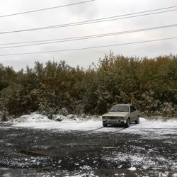 Car on snow covered trees against sky