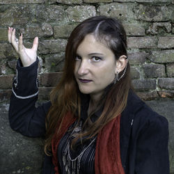 Portrait of teenage girl standing against stone wall