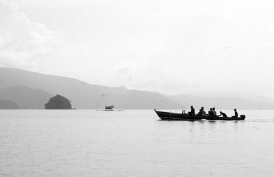 People on boat sailing in sea against sky