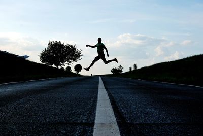 Full length of man skateboarding on road against sky