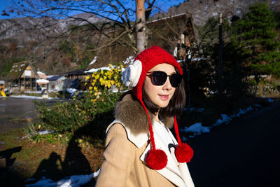 Portrait of young woman wearing sunglasses against trees