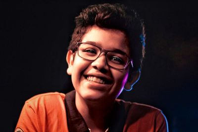 Portrait of smiling boy against black background