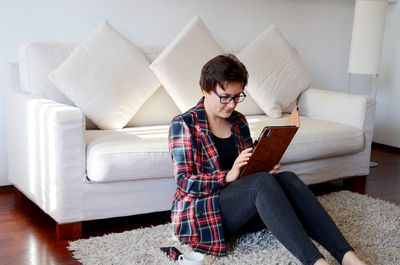 Young woman using laptop while sitting on sofa at home