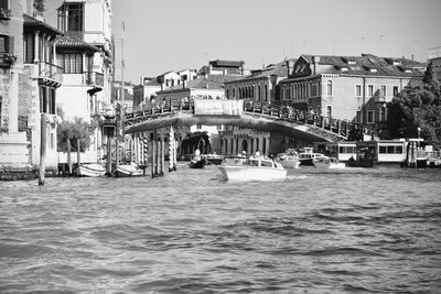 Boats in canal amidst buildings in city against clear sky