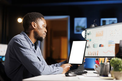 Side view of man using laptop at office