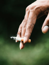 Close-up of cropped hand holding cigarette