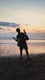 Full length of silhouette man on beach against sky during sunset