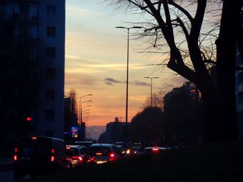 Cars on road in city against sky at sunset