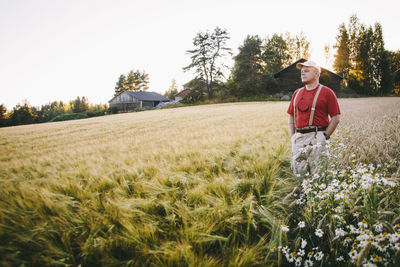 Mid adult man with hands in pockets standing on wheat field