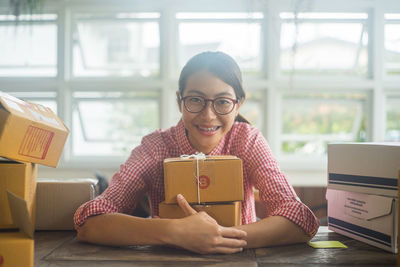 Portrait of smiling young woman holding wrapped gift at home