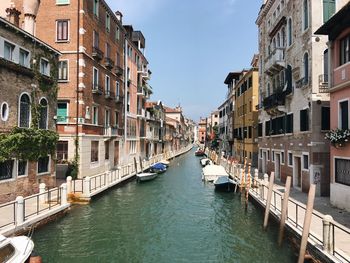 Canal amidst buildings in city against sky