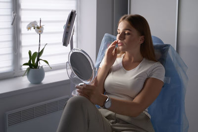 Young woman using mobile phone while sitting at home