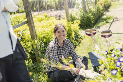 Happy woman looking away while sitting in greenhouse