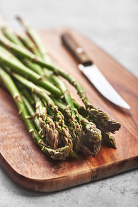 Fresh asparagus with a knife on a wooden background