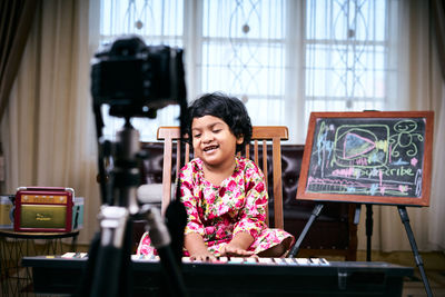 Cute girl playing piano while sitting at home