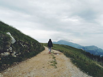 Rear view of woman walking on mountain against sky