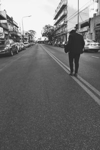 Rear view of man walking on road in city