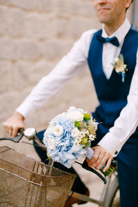 Midsection of man holding flower bouquet