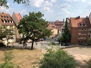 Trees and buildings in town against sky