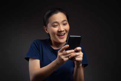 Mid adult man using mobile phone against black background