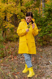 Cheerful young woman in a yellow raincoat and yellow boots poses for the camera. person