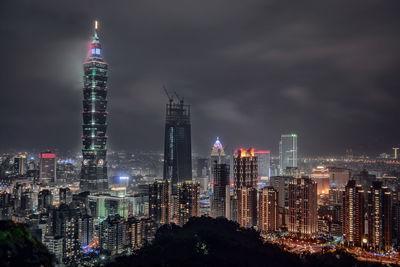 Illuminated modern buildings against sky at night