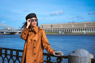 Young woman wearing sunglasses standing by railing